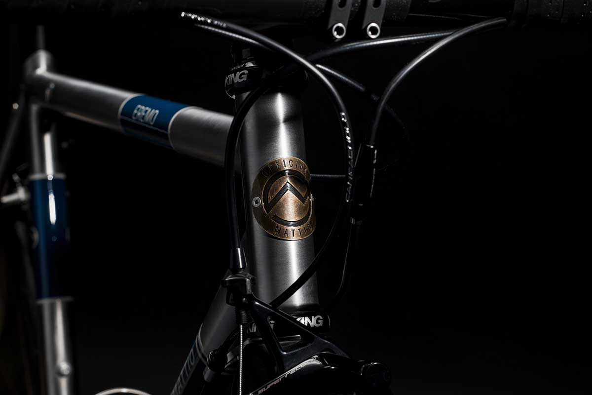 Bicicletta Officine Mattio modello EREMO CLASSIC, telaio in acciaio inossidabile elegante, fotografia dettaglio telaio, manubrio e logo OM