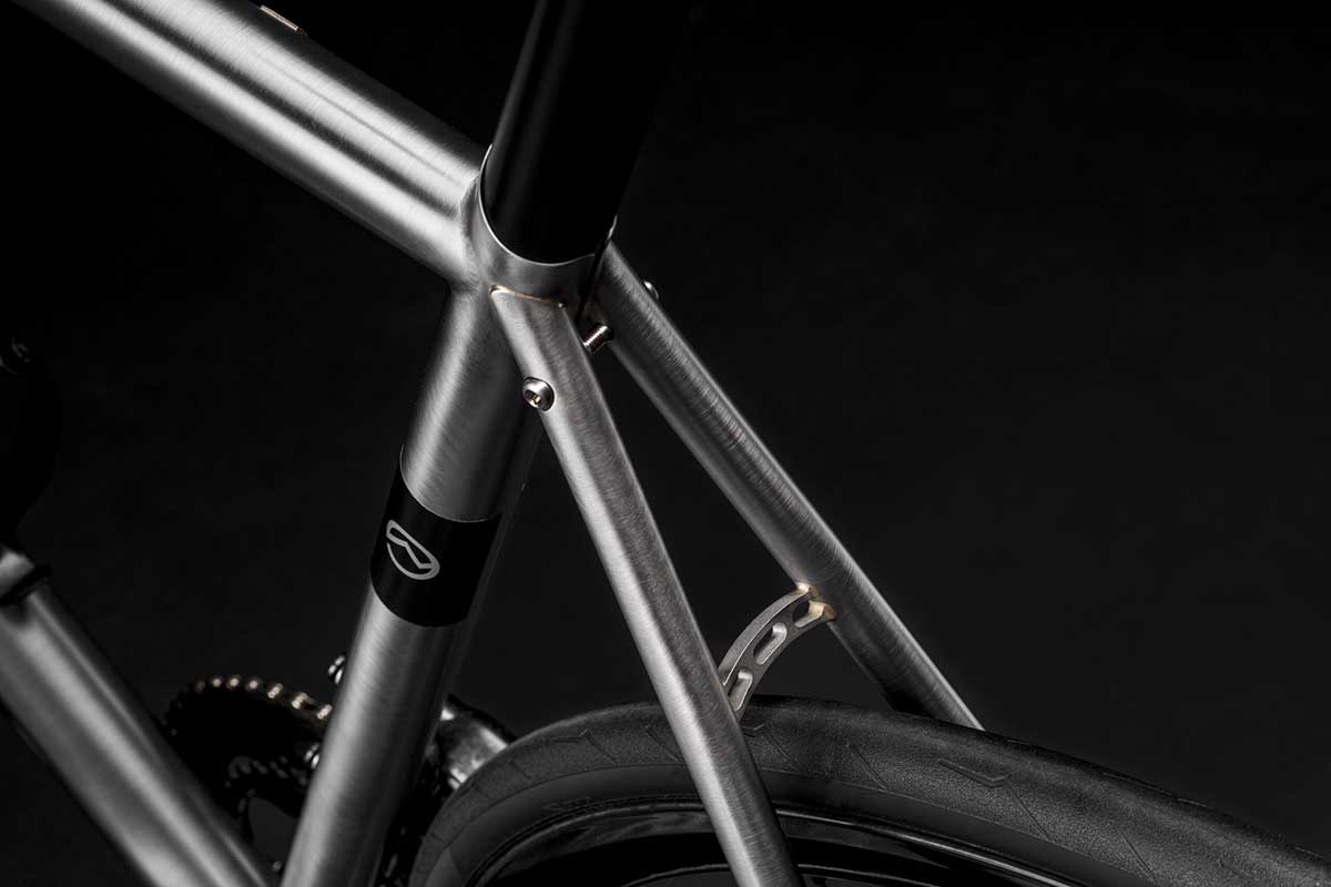 Bicicletta Officine Mattio modello EREMO DISC, telaio in acciaio inossidabile e freni innovativi, fotografia dettaglio telaio e logo OM